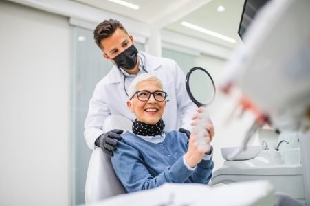 Beautiful senior woman having dental treatment at dentist’s office. Dentist is wearing protective face mask due to coronavirus pandemic.. Beautiful senior woman having dental treatment at dentist's office. Dentist is wearing protective face mask due to coronavirus pandemic.
